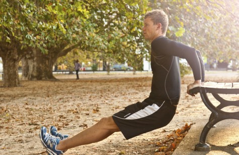 MAN EXERCISING IN PARK PERFORMING 'DIPS'