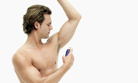 Young man spraying deodorant under his arm