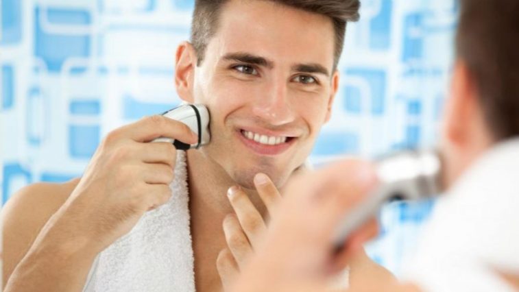 nam giới đang soi gương sử dụng máy cạo râu feature elle man