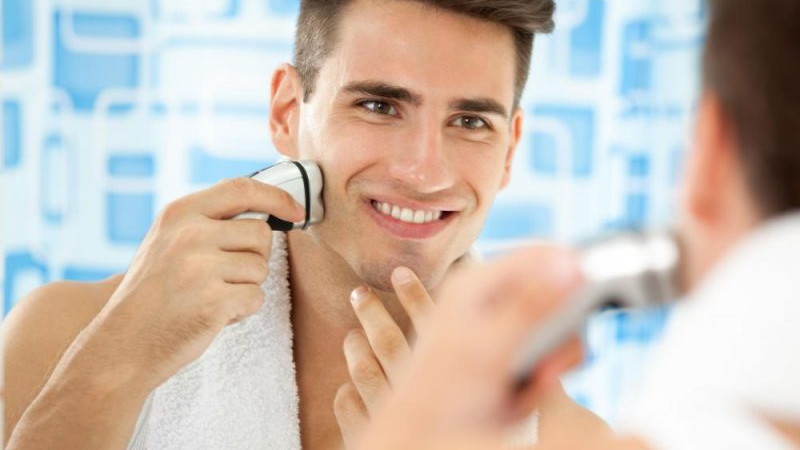 nam giới đang soi gương sử dụng máy cạo râu feature elle man