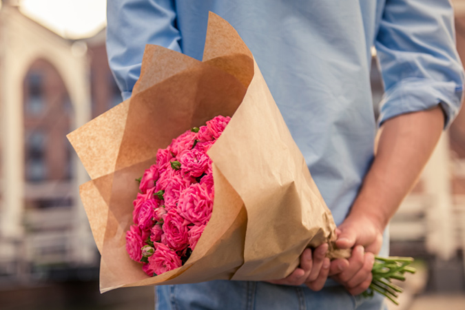 Người đàn ông giấu bó hoa sau lưng. 