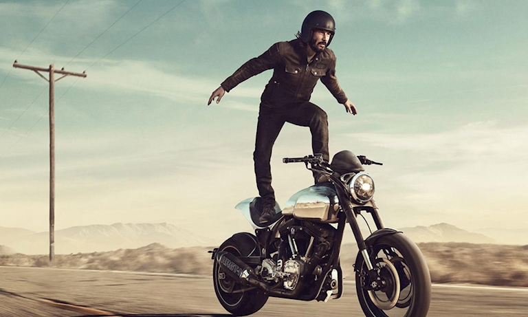 diễn viên Keanu Reeves đứng bên trên chiếc xe mô tô phân khối lớn