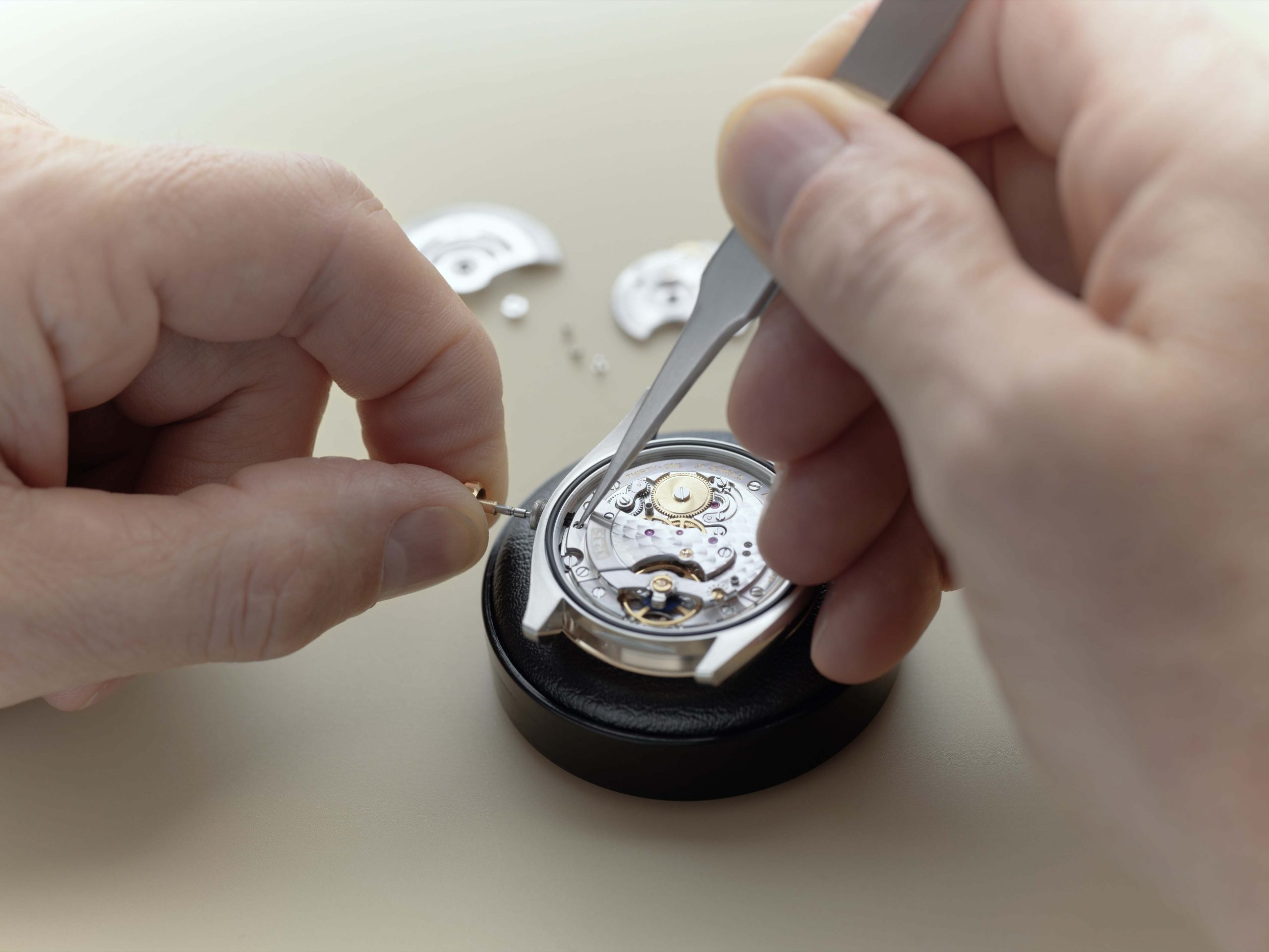 Dịch vụ Thế giới Rolex - Người thợ đồng hồ vặn một cách tỉ mỉ dây chính để loại bỏ lớp lõi khỏi đồng hồ.